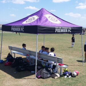athletes resting in the shade of a pop-up canopy